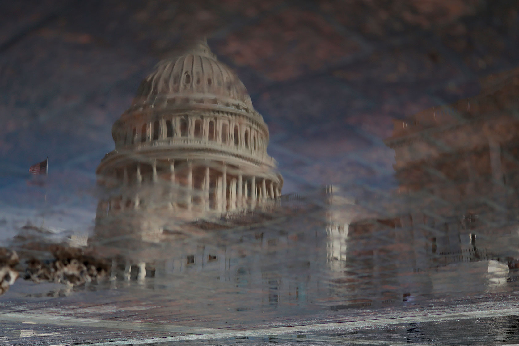 Front of Capitol Building refracted in puddle